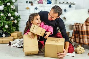 Father and daughter exchanging and opening Christmas presents photo