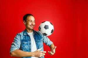 Handsome man holding a soccer ball over red backgound photo