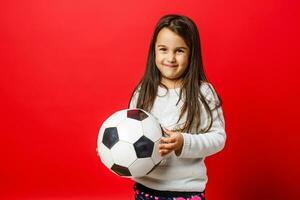 contento pequeño niña sonrisas con fútbol pelota en manos foto