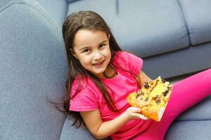 pequeño niña con grande Pizza a hogar foto