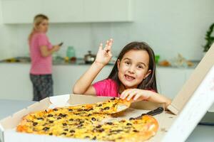 pequeño niña con grande Pizza a hogar foto