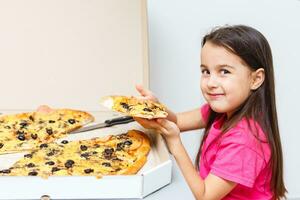 A young girl is eating a piece of pizza photo