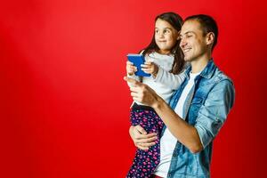 portrait of father and pretty daughter travelling together, Studio shot, red background photo