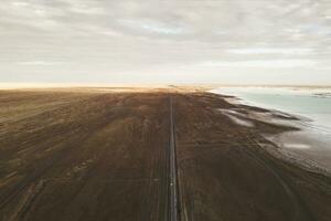 Straight road by the salt lake with wide flatlands background. photo