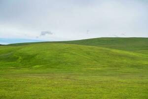 Grassland and mountains in a cloudy day. Photo in Kalajun grassland in Xinjiang, China.