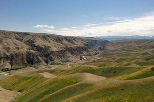 Mountain peaks and grassland are under white clouds. photo