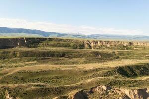 Mountain peaks and grassland are under white clouds. photo