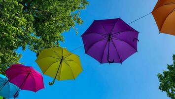 In the park there are colorful umbrellas hovering over the street. Street Decoration. photo