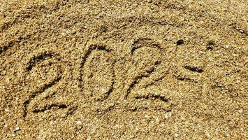 The numbers 2024 are written on the sandy beach. The concept of the new year photo