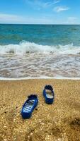 Blue slippers on the beach on the sand against the background of the sea photo