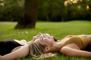 Two pretty young women laying on grass photo