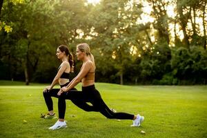 Two pretty young women stretching in the park photo