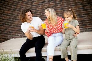 Family with a mother, father and daughter sitting outside on the steps of a front porch of a brick house photo