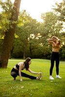 Two pretty young women stretching in the park photo