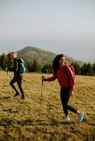 Smiling couple walking with backpacks over green hills photo