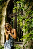 Pretty young woman using mobile phone by the old house with ivy photo