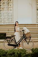 Young woman with white bichon frise dog in the basket of electric bike photo