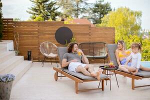 Family with a mother, father and daughter sitting on the deck chairs by the swimming pool photo