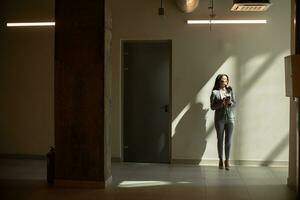 Young business woman using mobile phone in the office hallway photo