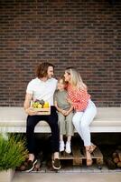 Family with a mother, father and daughter sitting outside on the steps of a front porch of a brick house photo