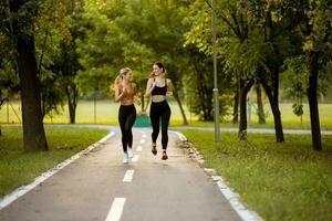 dos bonito joven mujer corriendo en el carril en el parque foto