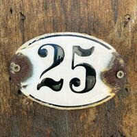 old rusty house number twenty-five 25 plaque on wall photo