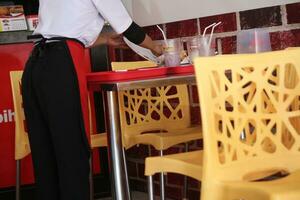 the clerk was cleaning up leftover food on the fast food restaurant dining table. photo