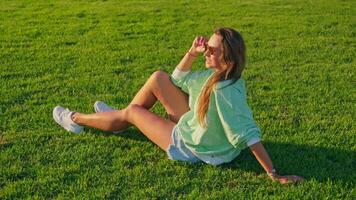 Beautiful girl sitting on the grass at sunset video