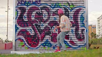 uma menina dentro uma Rosa chapéu caminhando dentro frente do uma vibrante grafite parede video