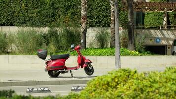 A vibrant red scooter parked on the side of a city street video