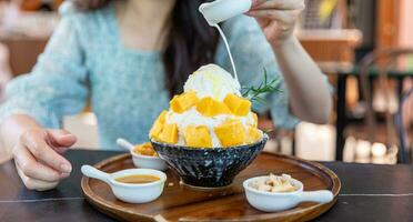 Shaved ice dessert with mango slices. Served with vanilla ice cream and whipped cream. Sweet dessert in Korean style. Local name, Bingsu. photo