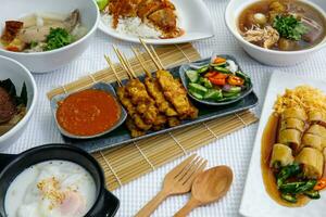 Pork Satay on plate. Grilled pork served with peanut dipping sauce,toasted bread and sweet sour sauce decorated with cucumber,onion and chili. One of the best Thai street food. photo