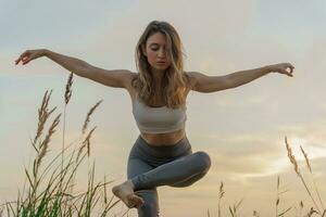 Meditation and harmony and balance of a person, mental health. The woman is slender, flexible body, practicing yoga exercise beautiful asana. Fitness on the background of sunset. photo