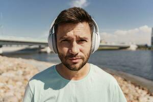 A portrait of a man listening to a music playlist with headphones, an athlete is close. photo