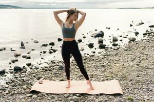 Training yoga pose lotus outdoors in fitness clothes, healthy lifestyle. Harmony and balance and zen. Mental health a female coach meditates using a mat. photo