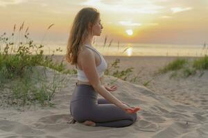 Meditation and harmony and balance of a person, mental health. The woman is slender, flexible body, practicing yoga exercise beautiful asana. Fitness on the background of sunset. photo