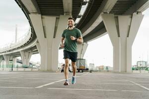 A runner in full-length fitness clothes, running shoes. Uses a sports watch to measure heart rate. Mental health in a man, a trainee does warm-up exercises. photo