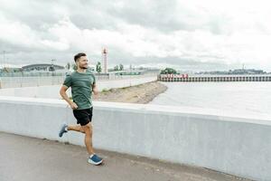 Runner trainer in full-length fitness clothes, running sports shoes and fitness watches. Motivation a male athlete training does warm-up exercises. Mental health of a person. photo