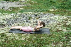 The trainer is engaged in pilates asana and stretching a slim body.  Young exercise woman yoga workout. The asana pose is harmony with nature. Uses mat meditation and mental health of a person. photo