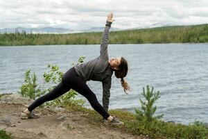 Training in nature, improves Pilates and stretching. Confident and harmony in a healthy human body.  The trainer doing the yoga asana exercise, uses a mat. photo