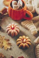 Burning candles shape of pumpking, mug with aiutumn drink, leaves and cinnamon photo