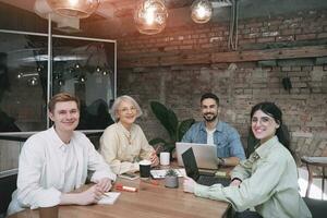 contento negocio personas sentado en un reunión habitación a un mesa y trabajando juntos en un proyecto, utilizando computadoras portátiles puesta en marcha, trabajo colaborativo, administración concepto foto