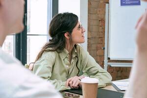 Portrait of smiling beautiful young lady in smart casual clothes listening presentation in meeting room in the office. Startup concept photo