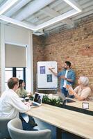 Man standing near a flipchart and talking about a new project to colleagues during a meeting in the office. Startup, coworking, management concept photo