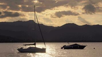 Silhouetten von Yachten gegen das Hintergrund von Sonnenuntergang und Berg Landschaft video