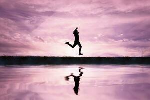 man jumping over a pond with a sunset background photo