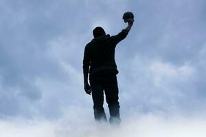 man silhouette among clouds in the mountain photo