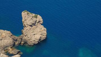 The rock juts out of the sea high above the water video