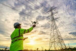 Asian engineers are launching drones to inspect the power station for a planned work by generating electricity from a high-voltage transmission tower at sunset. photo