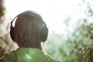 Woman in headphones against bright sunlight photo